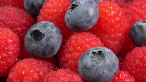 Ripe raspberries and blueberry close up rotate in a wooden bowl. Juicy fresh blueberry and raspber