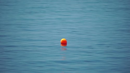 Orangenboje, die auf der Meeresoberfläche schwimmt, Wellen, Konzept der Sicherheit des menschlichen Lebens Orange Safety
