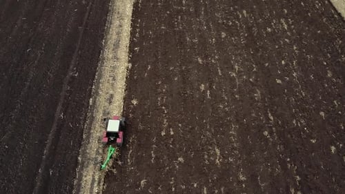 Red tractor plowing the field in Ukraine