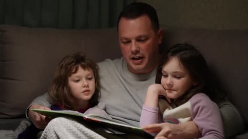 Dad Reading Story to Two Young Daughters