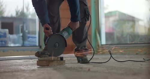 Worker grinding concrete with angle grinder, creating sparks, wearing protective helmet, intense