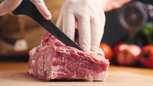 Chef Cutting Raw Meat in Kitchen