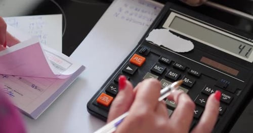 Close Up And Pan Of Female Accountant Using Calculator To Calculate Sales Receipts
