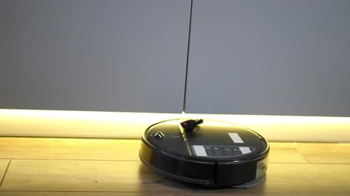 Robot Vacuum Cleaner Moving Across Wood Floor