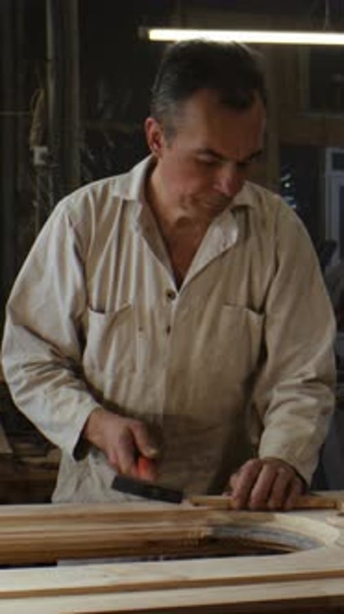 Craftsman Aligns Wooden Block with Frame Using Small Hammer