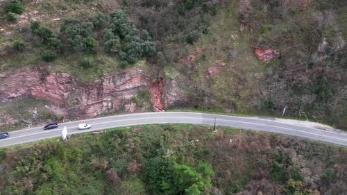 Cars Drive Along a Curved Mountainous Section of the Highway Aerial View