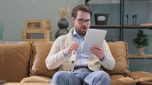 Excited Man on Couch Using Tablet