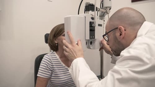 Optiker führt Augenuntersuchung an einem Patienten mit Geräten im Untersuchungsraum durch Erwachsener