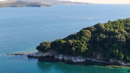Aerial Drone Shot of a Secluded Green Island Cape with Rocky Cliffs and Clear Turquoise Water