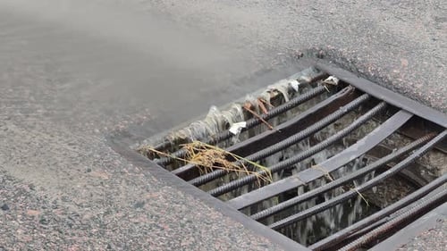 Stormwater Runoff Draining Into a Street Sewer Grate