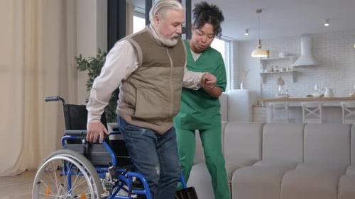 Caring Nurse Helps Senior Man Out of Wheelchair