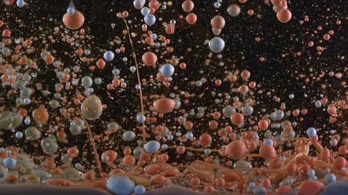 Bubbles of orange and blue paint mixing