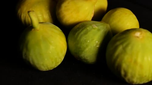 A shot of a few frresh figs spinning on a black surface, with a very short deep of field.