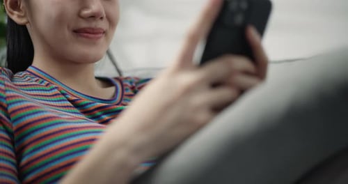 Smiling Woman Using Smartphone Relaxing on Sofa