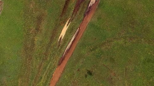 Dirtbike rider going by on muddy track, top view drone shot