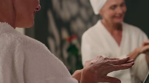 Woman Applies Lotion in Front of Mirror