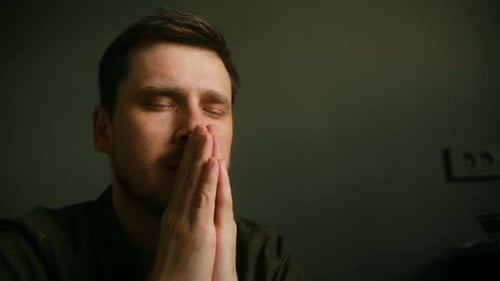 In Dark Room Religious Person Sits Hands Clasped in Prayer Embodying Hope Faith This Intimate Moment
