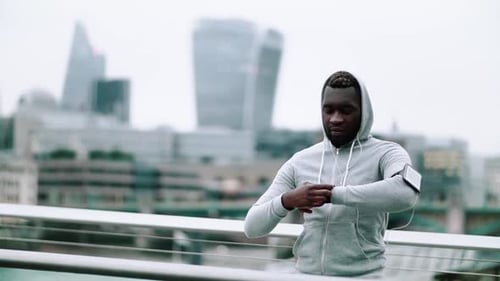 Black Man Runner with Smart Watch and Smartphone on the Bridge In