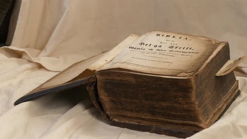 Male hand shuts the cover of very old thick historical bible. Close up. Static shot.