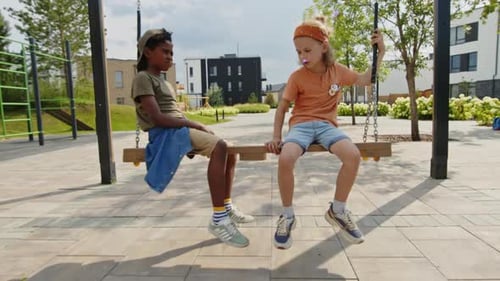 Happy Multiethnic Kids Relaxing on Swing in Playground