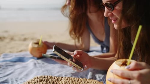 Cheerful Girls Tan Surf Internet on Phones at Sandy Beach Happy Ladies Sunbathing Texting on Devices