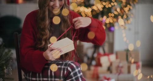 Young Woman Opens Christmas Present with a Smile