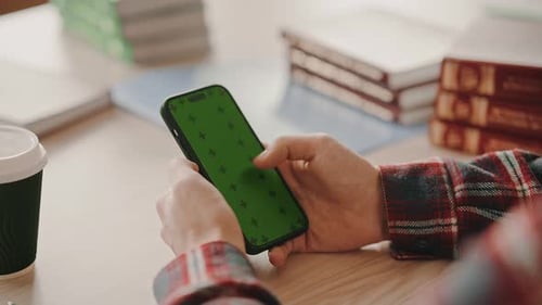 Student using smartphone with green screen mockup