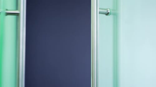 Close up of a man's hand opening a glass office door holding a metal doorknob in a modern building.