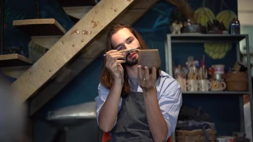 Male craft crockery and potter tableware master at workplace wearing apron closeup
