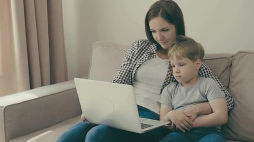 Mother and Son Using Laptop on the Couch