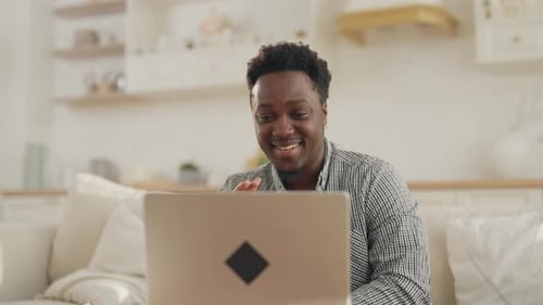 Man Smiling and Waving During Video Call at Home