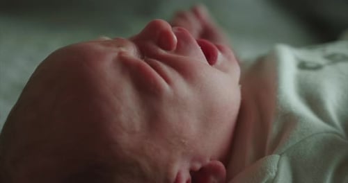 Authentic close up shot of a newborn baby is crying during his mother is changing he on a bed.