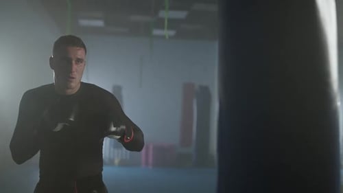 Fighter Trains His Punches in the Boxing Gym a Man Boxer Beats a Punching Bag Slow Motion