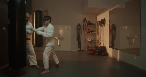 Boy and Man Practice Martial Arts Punching in Dojo