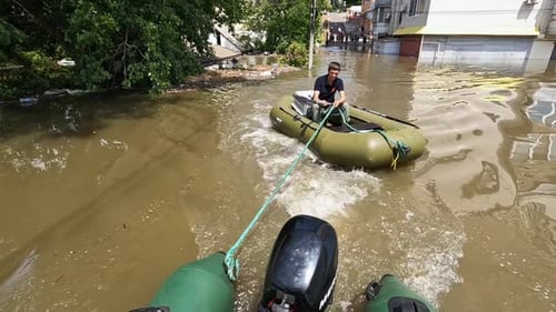 Voluntarios navegan en barco para evacuar animales y personas tras la detonación de la energía hidroeléctrica