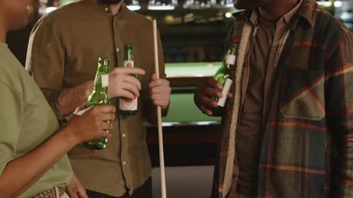 Friends Clinking Bottles of Beer Celebrating St Patricks Day in Billiard Club