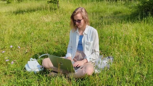 Woman Works on Laptop in Sunny Grassy Field