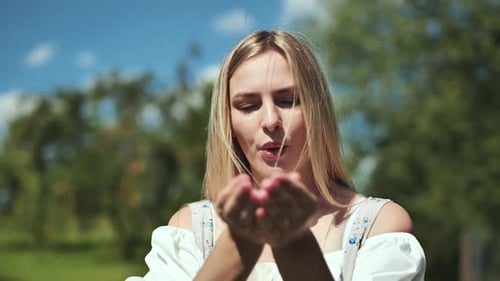 Woman Smiling Blowing Confetti Outside on Sunny Day