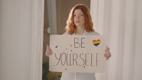 Lächelnde junge Frau, die ein Plakat mit der Botschaft „Sei du selbst“ hält, LGBT-Mädchen, Lesbisch