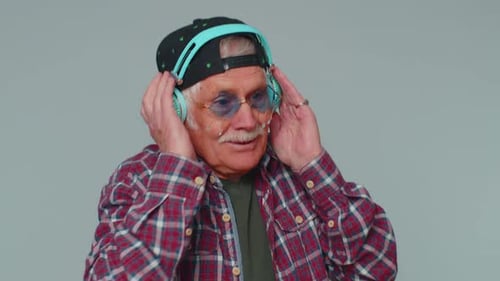 Joyeux et séduisant homme écoutant de la musique avec des écouteurs et dansant en discothèque, jouant autour de s'amuser