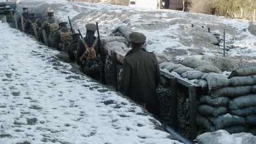 World War One British soldiers walk through a trench towards the front line. Snow covered sandbags l