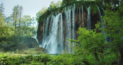 Large Majestic Waterfall Flowing Down Mosscovered Cliff Into Lake Below