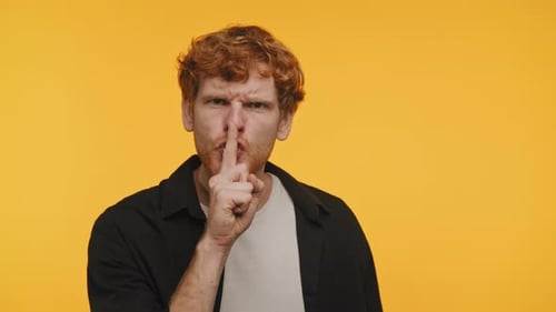 Man Making Silence Gesture on Yellow Background