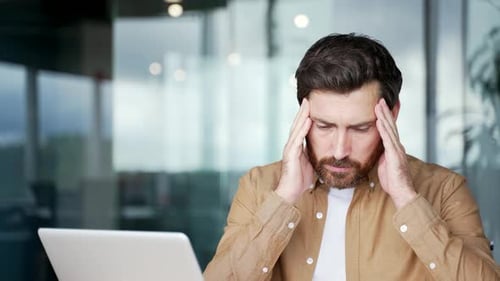 Businessman has depression suffering from mental pain sitting at workplace in office. Sad male holds
