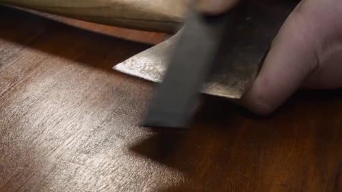 Old used axe head is made new again by sharpening edge with whetstone
