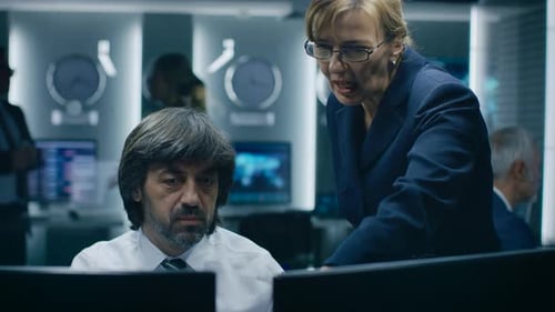 Man working at computer with woman pointing