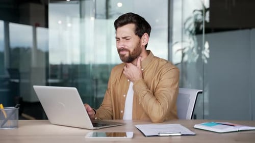 Man in Office With Sore Throat Rubs Neck