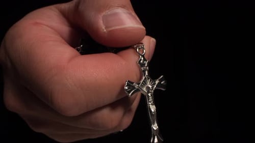 Hand Holding Rosary Beads and Crucifix on Dark Background