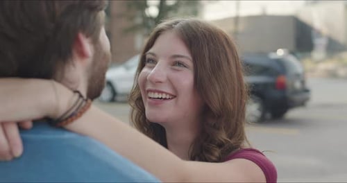Close up of woman's face with her arm around man talking to each other.