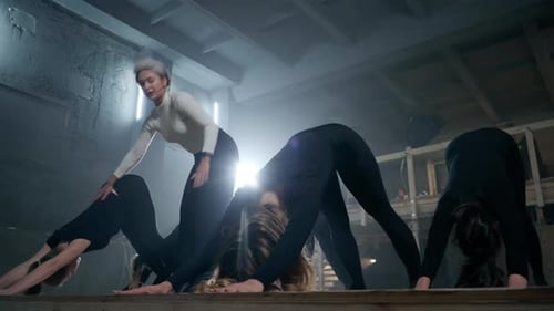 Yoga Instructor Helping Young Women Stretch